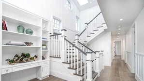 Ein geräumiger Flur mit einer Treppe zu den oberen Stockwerken, weißen Wänden und einem Holzboden.