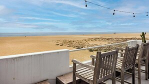 Vista sulla spiaggia dal balcone, con sedie di legno e una ghirlanda luminosa.