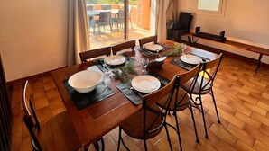 Een eetgedeelte met een houten tafel voor vier personen, omringd door stoelen.