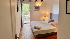 Een slaapkamer met een bed, een bedlampje en uitzicht op het omliggende landschap door een raam.