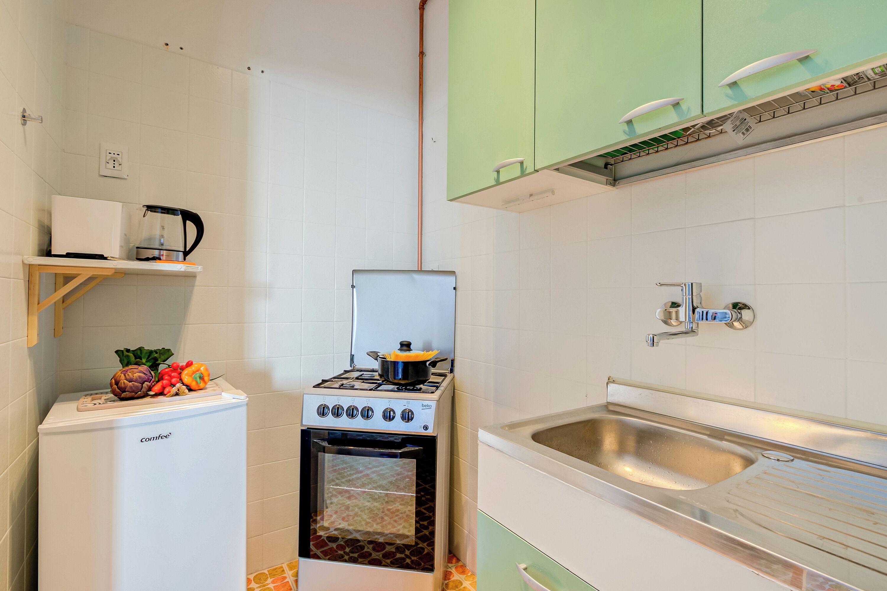 A compact kitchen with a stove, oven, and sink.
