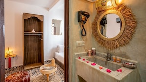 Une salle de bain avec un miroir rond, un sèche-cheveux et un porte-serviettes.