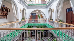 Un intérieur à plusieurs niveaux, agrémenté de rampes décoratives, d’un escalier central et d’un balcon offrant une vue panoramique.