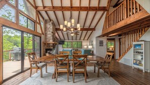 Une salle à manger spacieuse avec une grande table et des chaises en bois, un lustre et une cheminée en pierre.