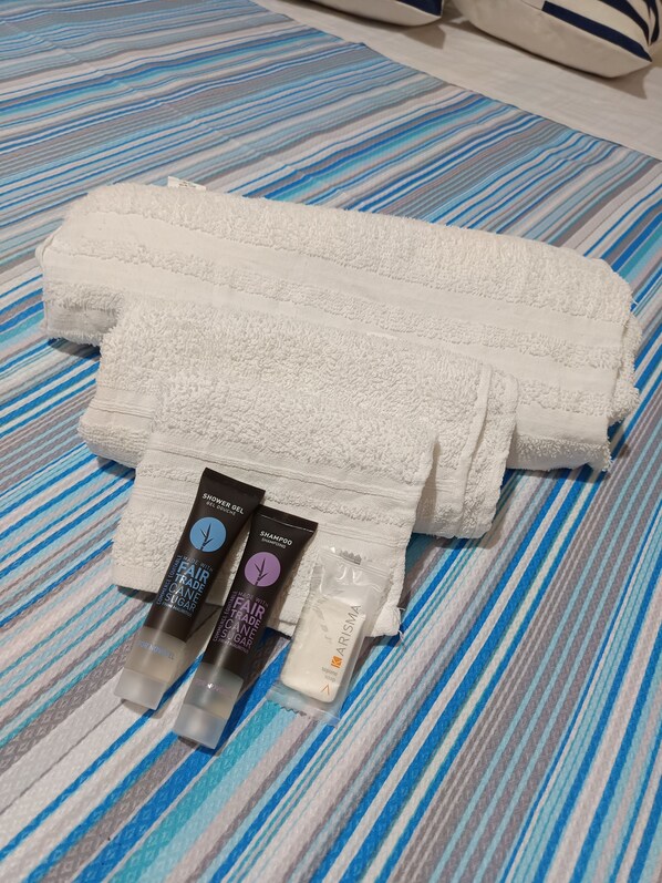 A neatly folded white towel on a striped bedspread.