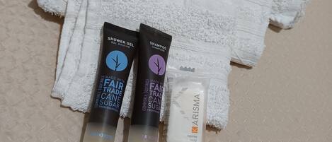 A white towel, two hair care products, and a soap bar on a textured surface.