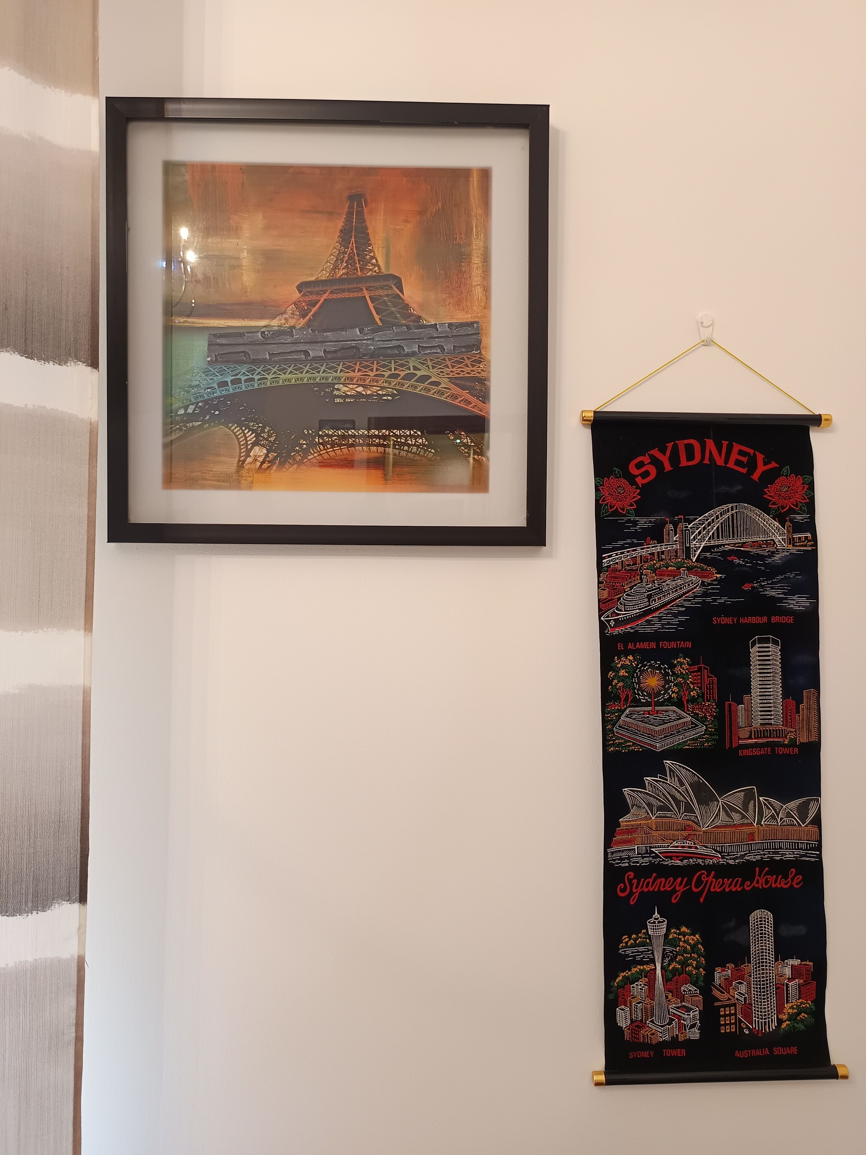 A framed painting of the Eiffel Tower and a Sydney-themed poster.