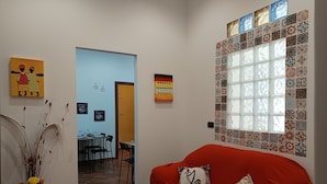 A cozy living room with a red sofa, a decorative vase with flowers, and a window with patterned tiles. - A casa di Peppe (Palermo)
