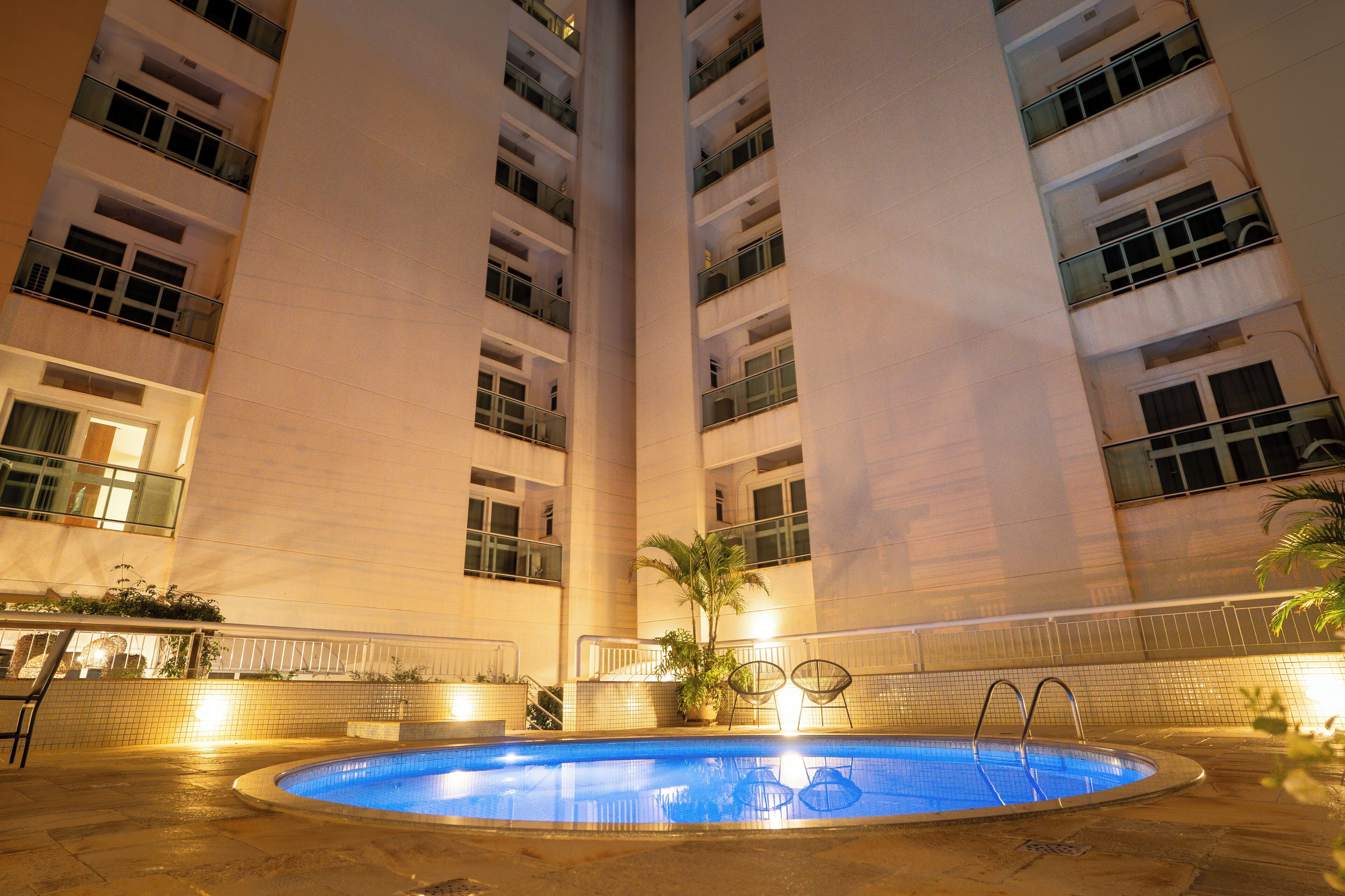 A swimming pool with a view of a tall building with multiple balconies.
