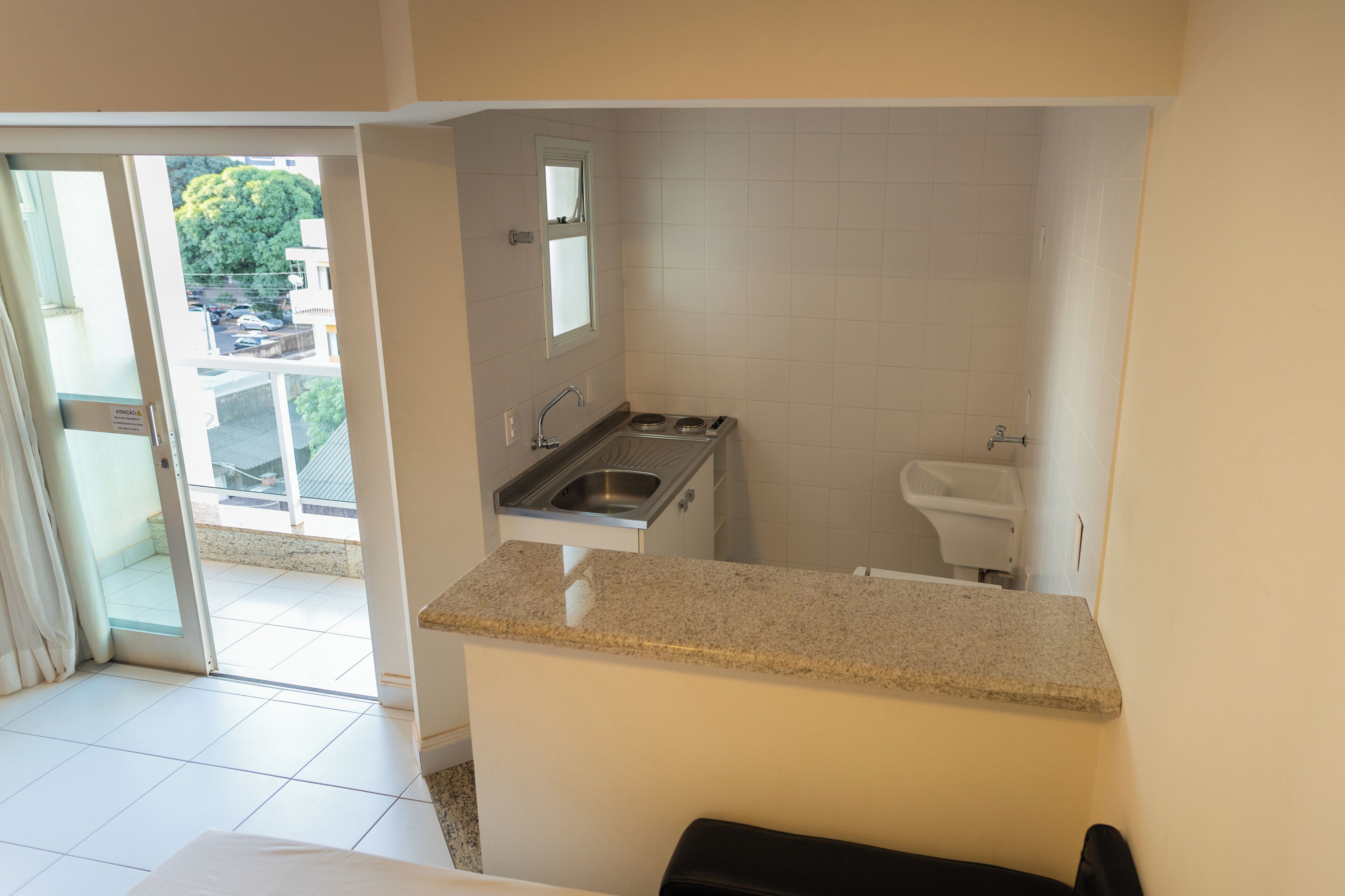 A compact kitchen with a sink, a window, and a view of the outside.