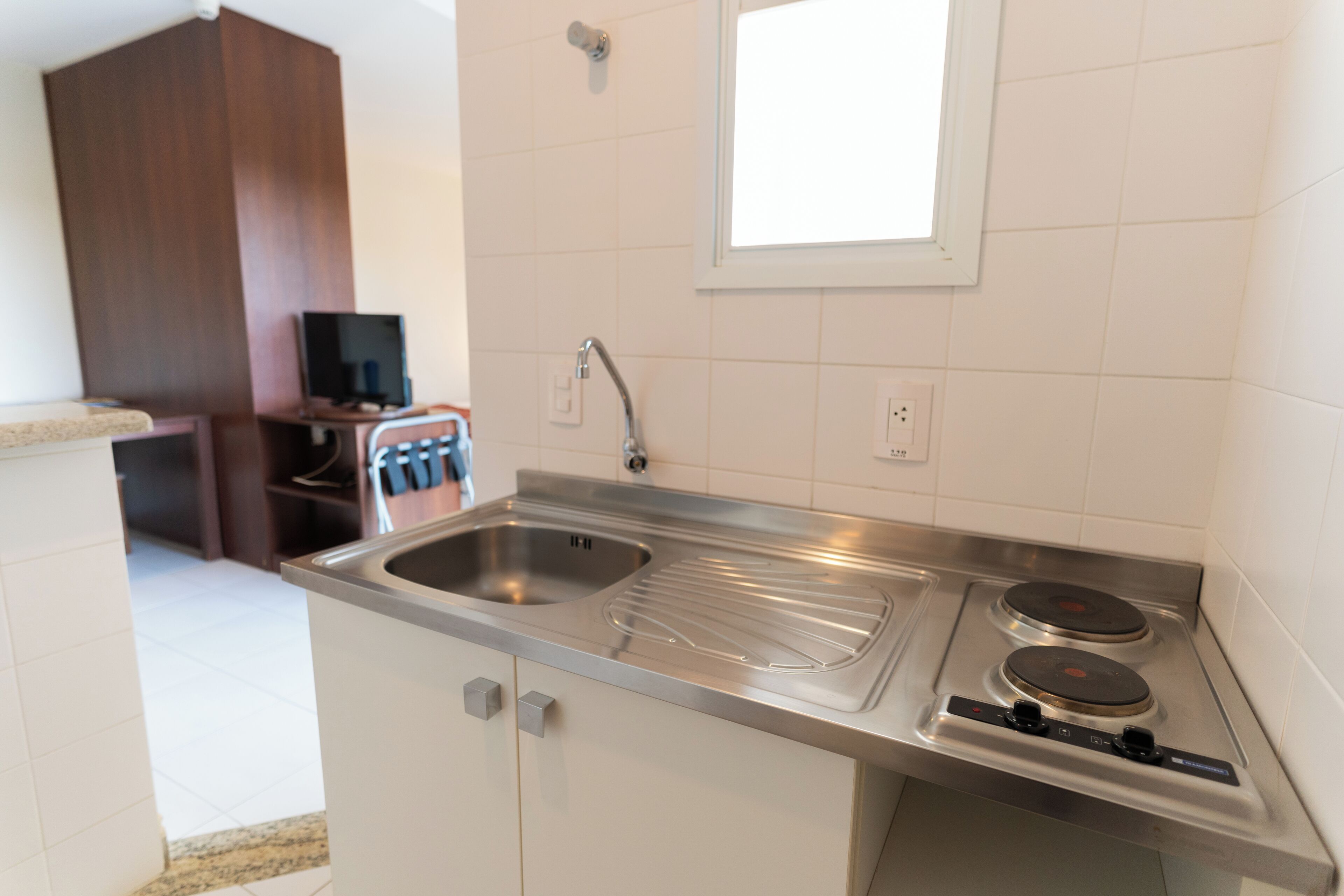 A kitchen with a stainless steel sink, double electric stove, and a window above the sink.