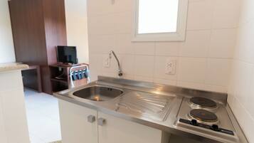 A kitchen with a stainless steel sink, double electric stove, and a window above the sink.