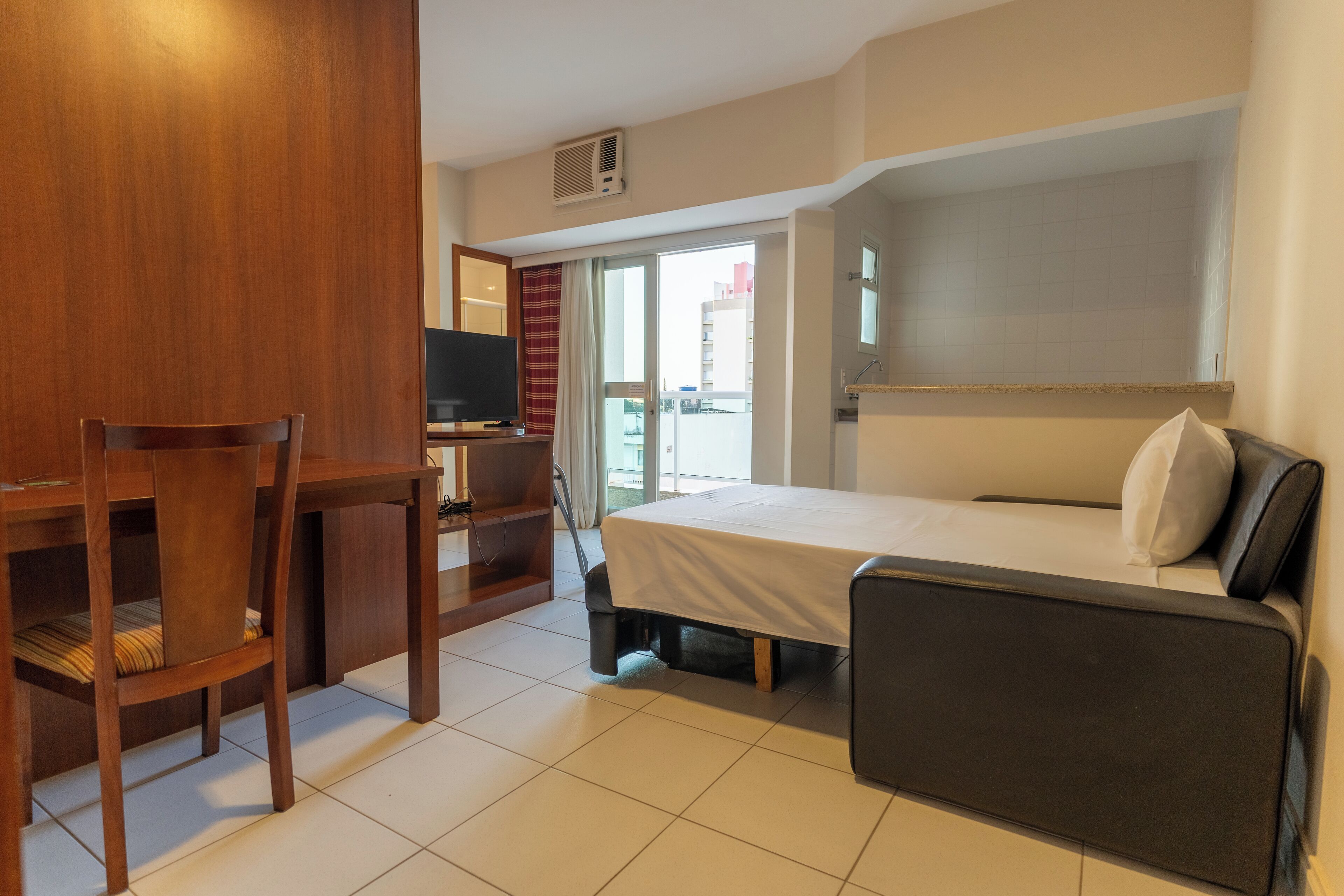 Una habitación de hotel con cama, escritorio, silla y televisión.