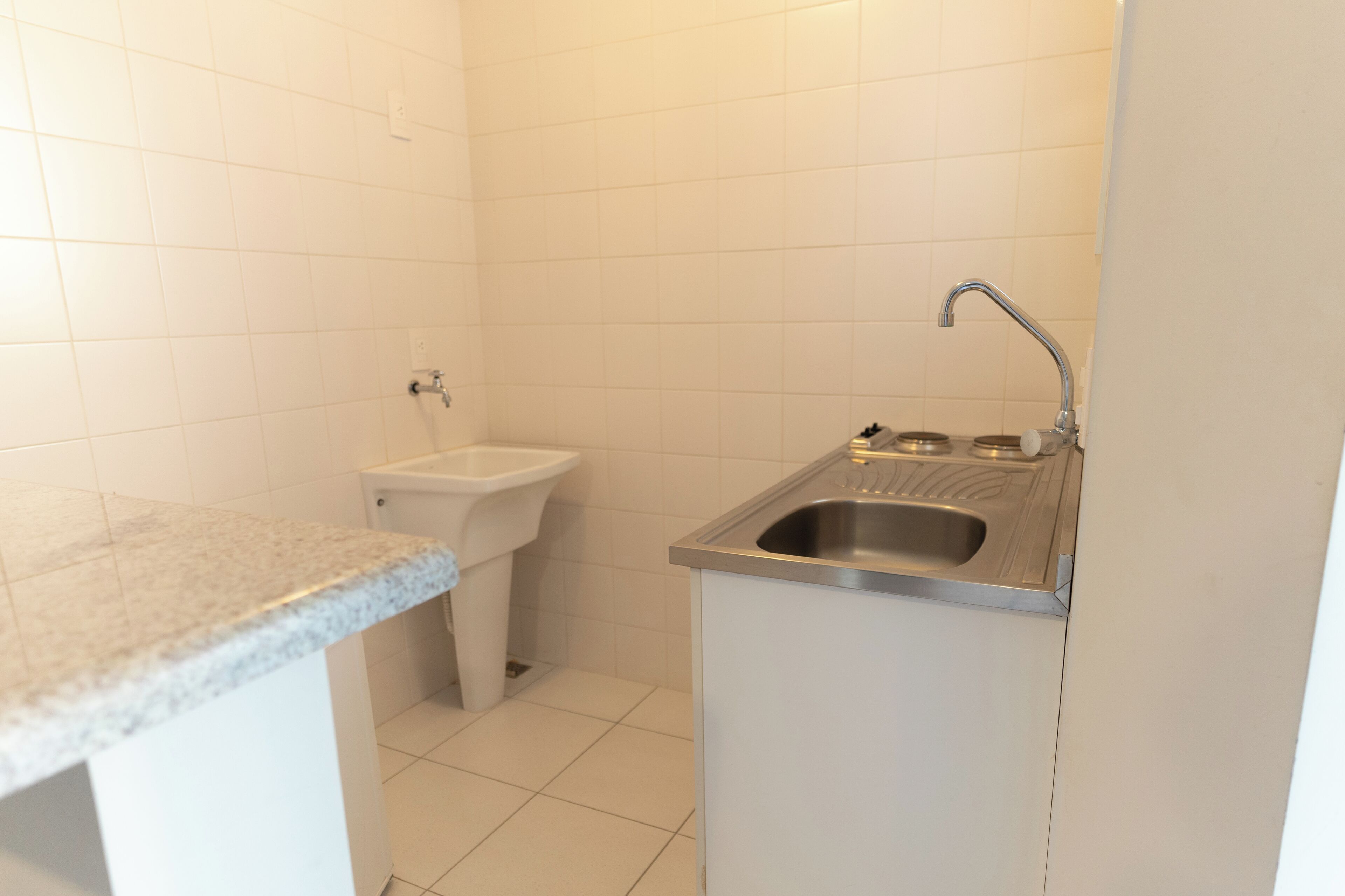 A small kitchen with a sink, a toilet, and a countertop.