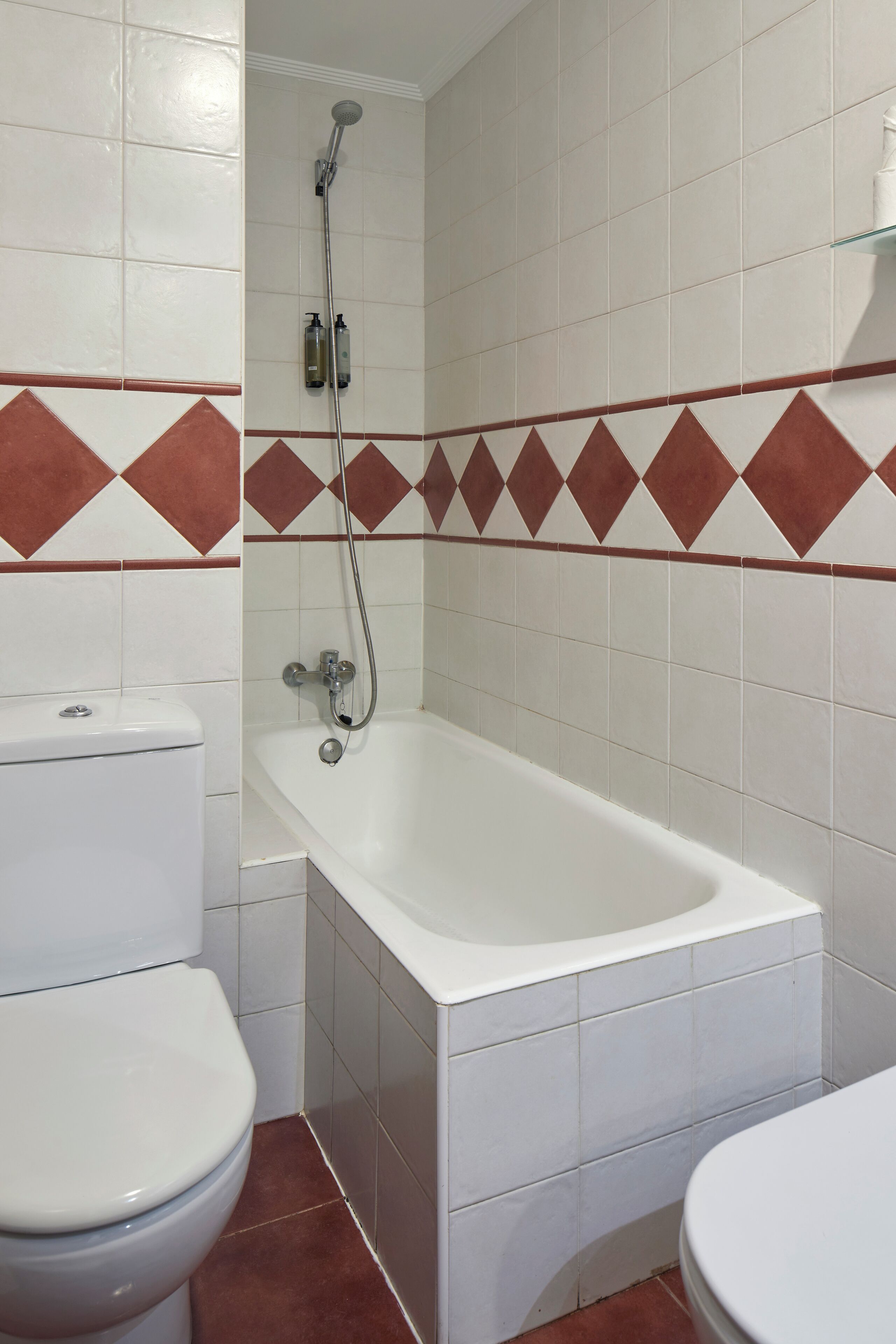 A bathroom with a white bathtub, a toilet, and a shower.