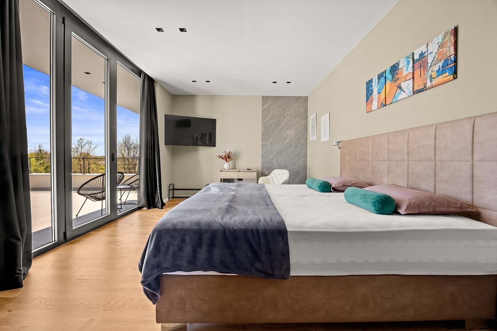 Et moderne soveværelse med en stor seng, et fjernsyn, en marmorvæg og en balkon med en stol.