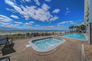 A pool area with a view of the beach and ocean, surrounded by lounge chairs and a fence. - Ocean Reef 1005 Beachfront, Heated Indoor & Outdoor Pools, Hot Tub, FREE Golf (Panama City Beach)