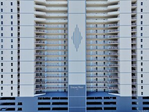 A high-rise hotel with multiple balconies, a central logo, and the name "Ocean Reef" at the bottom.