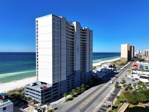 A high-rise hotel with multiple floors, a parking garage, and a view of the beach and ocean. - Ocean Reef 1005 Beachfront, Heated Indoor & Outdoor Pools, Hot Tub, FREE Golf (Panama City Beach)