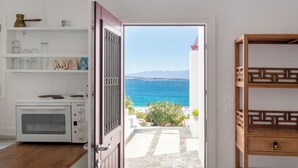 A kitchen with a view of the sea, a stone pathway, and a wooden cabinet.