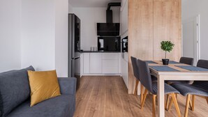 Una cocina moderna con armarios blancos, una campana extractora negra y una pared decorativa de madera.