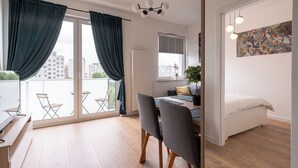 Un apartamento moderno con balcón, zona de comedor y cama.