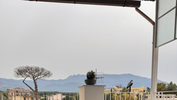 A balcony with a view of mountains, a chair, a table, and a polka-dotted cushion. - Vesuvius Pompeii (Pompei)