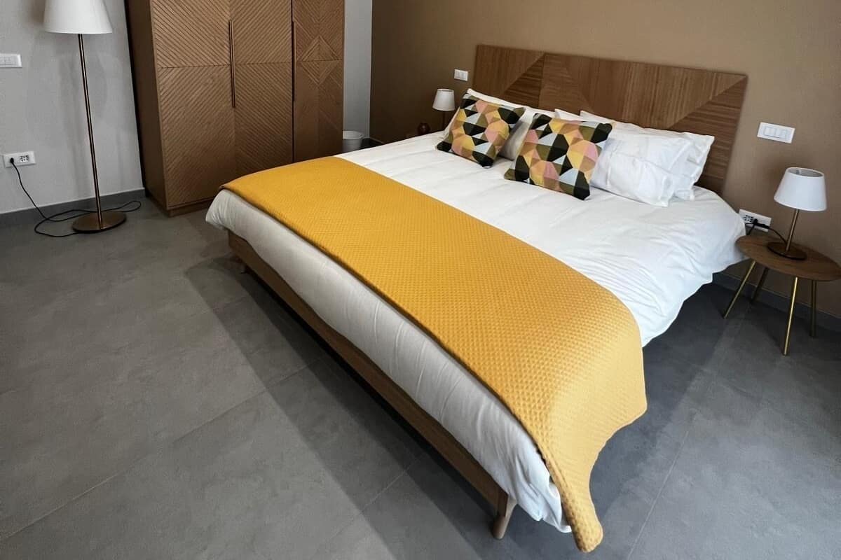 Una habitación de hotel moderna con una cama grande, un armario y una lámpara de pie.