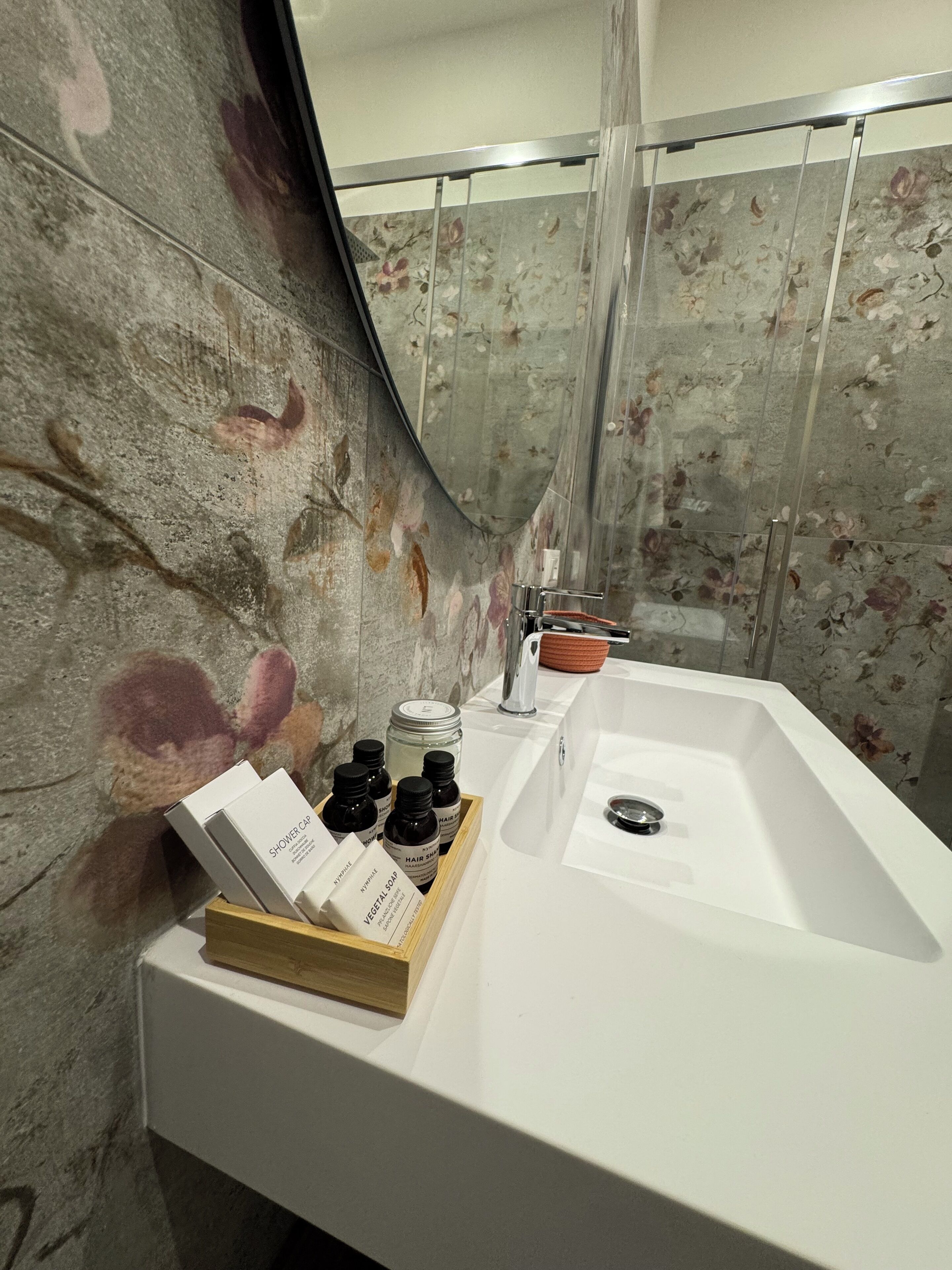 A bathroom with a shower curtain, a sink, and toiletries on the counter.