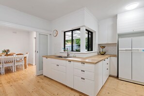 Una cucina moderna con mobili bianchi, un piano di lavoro in legno e una finestra incassata.