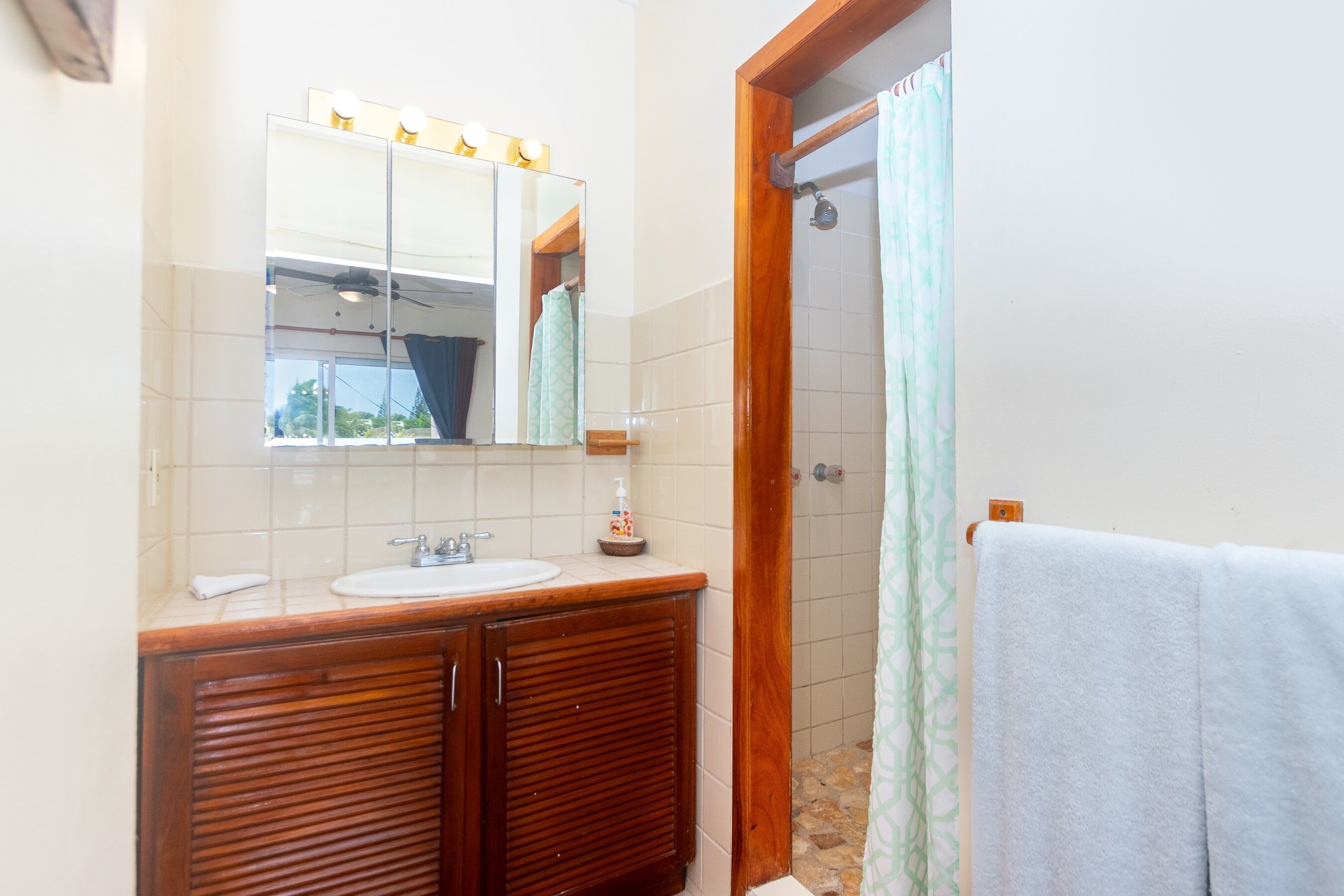 A bathroom with a wooden vanity, a sink, a mirror, and a shower with a curtain.