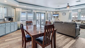 A spacious living area with a dining table, chairs, a sofa, and a television. - Shore Better Than Work 4 Bedroom Home by RedAwning (Rockport)