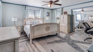 A bedroom with a bed, dresser, desk, chair, and a ceiling fan. - Shore Better Than Work 4 Bedroom Home by RedAwning (Rockport)