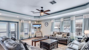 A spacious living room with leather sofas, a coffee table, and a ceiling fan. - Shore Better Than Work 4 Bedroom Home by RedAwning (Rockport)