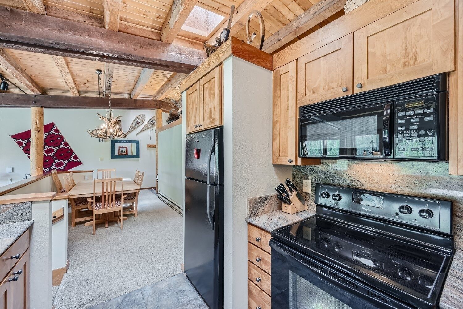 A kitchen with wooden cabinets, a black refrigerator, a microwave, and a stove.