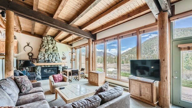A cozy living room with a stone fireplace, comfortable seating, and a large TV.