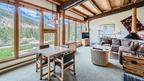 A spacious living room with large windows, a wooden ceiling, and a cozy seating area.