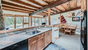 A spacious kitchen with a granite countertop, wooden cabinets, and a stone backsplash.