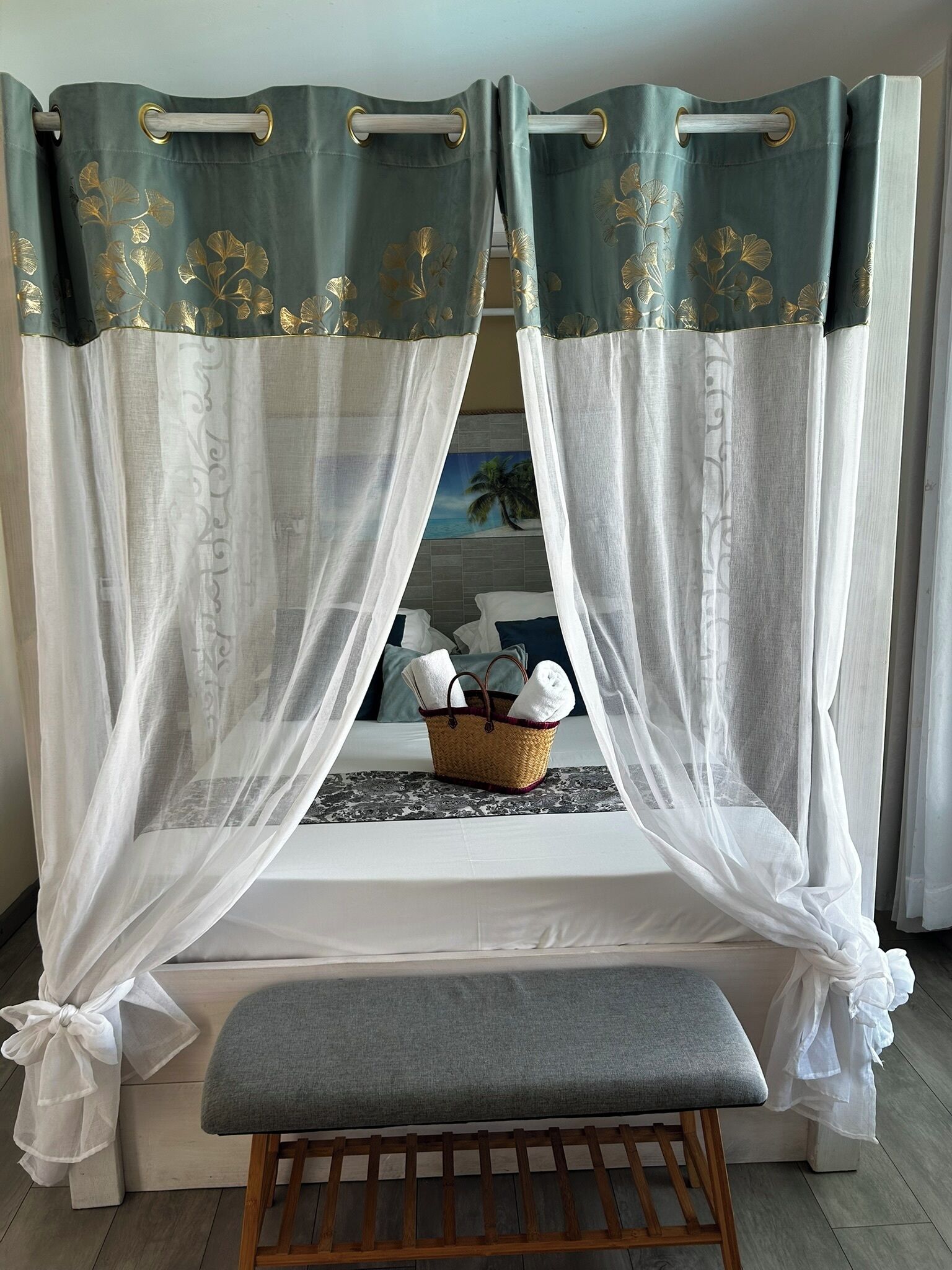 A room with a bed, a bench, and a basket with towels.