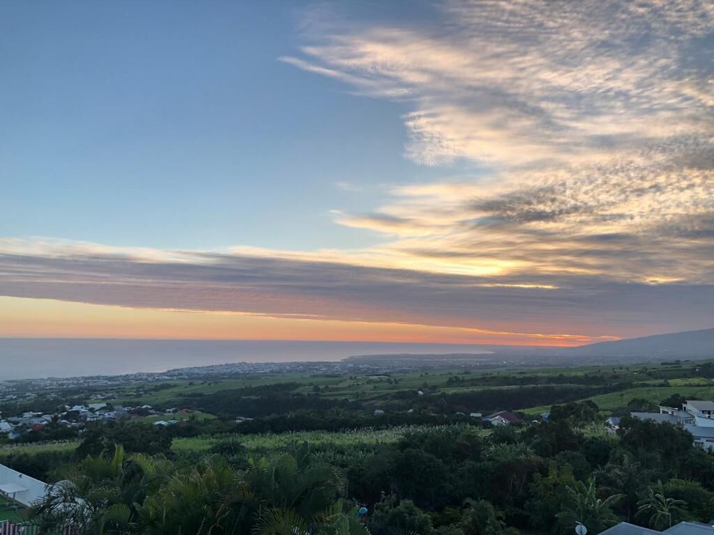 A landscape view with a clear sky, distant horizon, and scattered clouds.