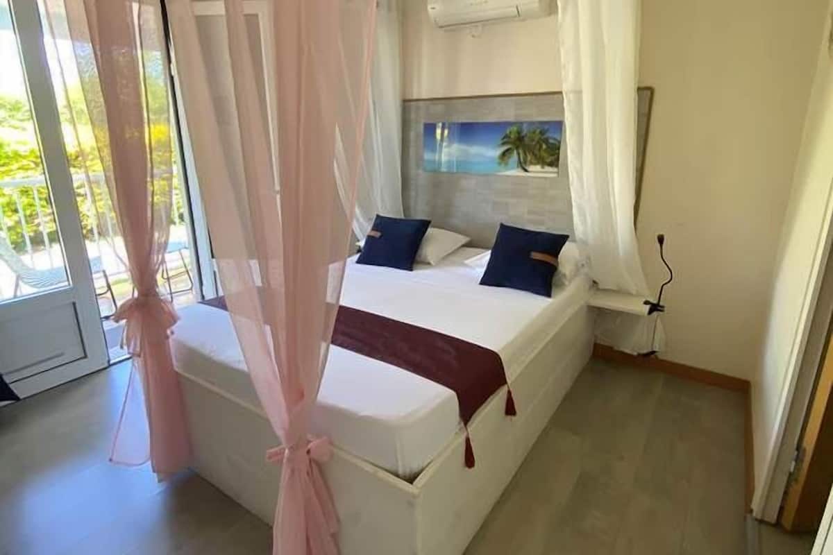 Un dormitorio con cama, una ventana con cortinas y un equipo de aire acondicionado.