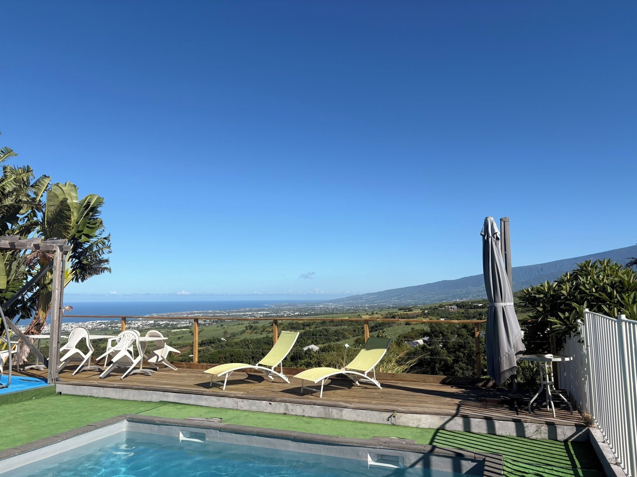 A pool with lounge chairs and a view of the ocean.