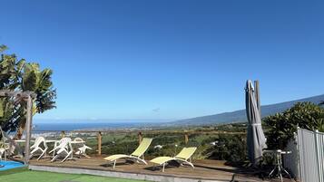 A pool with lounge chairs and a view of the ocean.