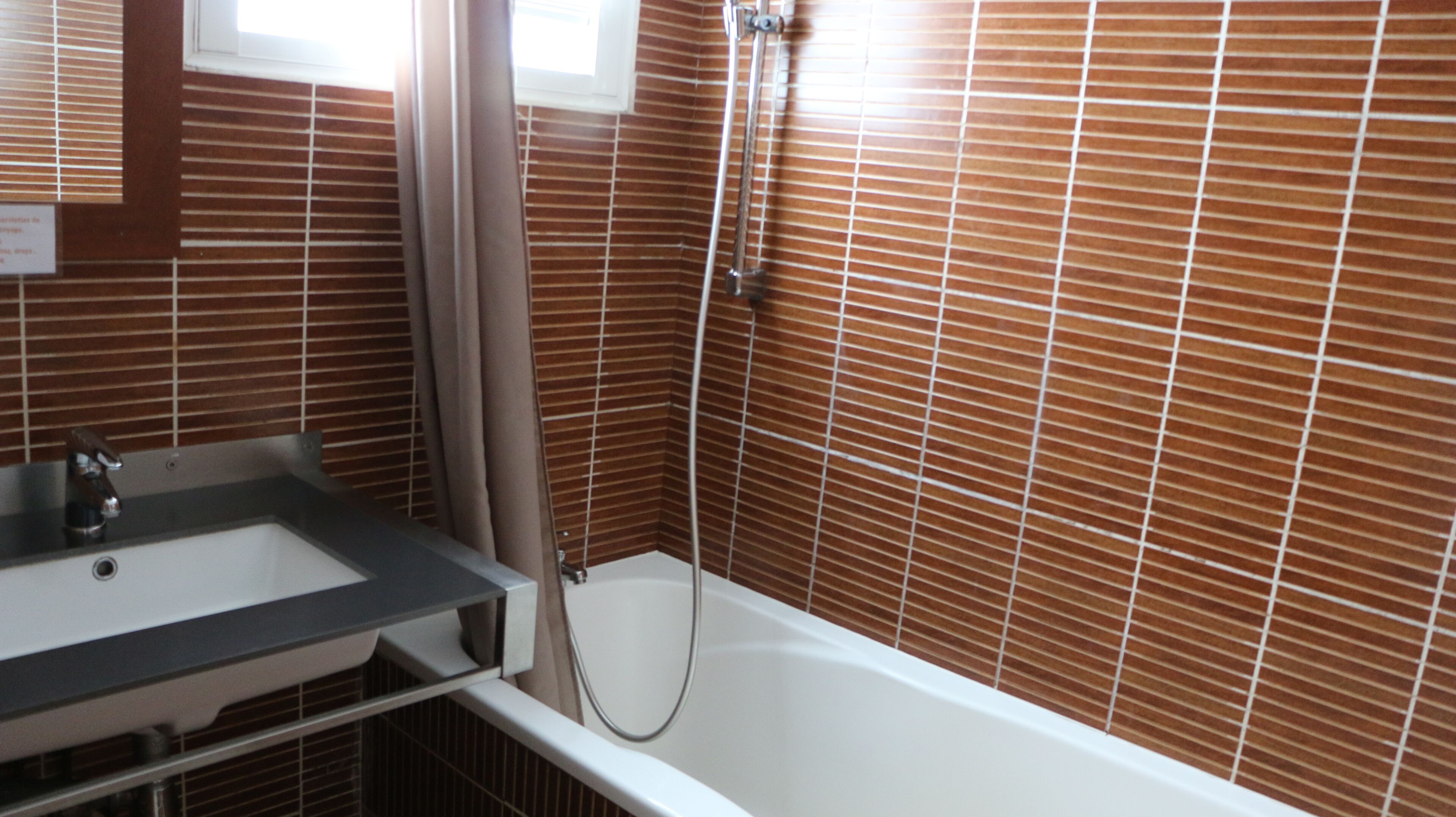 A bathroom with a white bathtub, a shower, and a sink with a mirror above it.