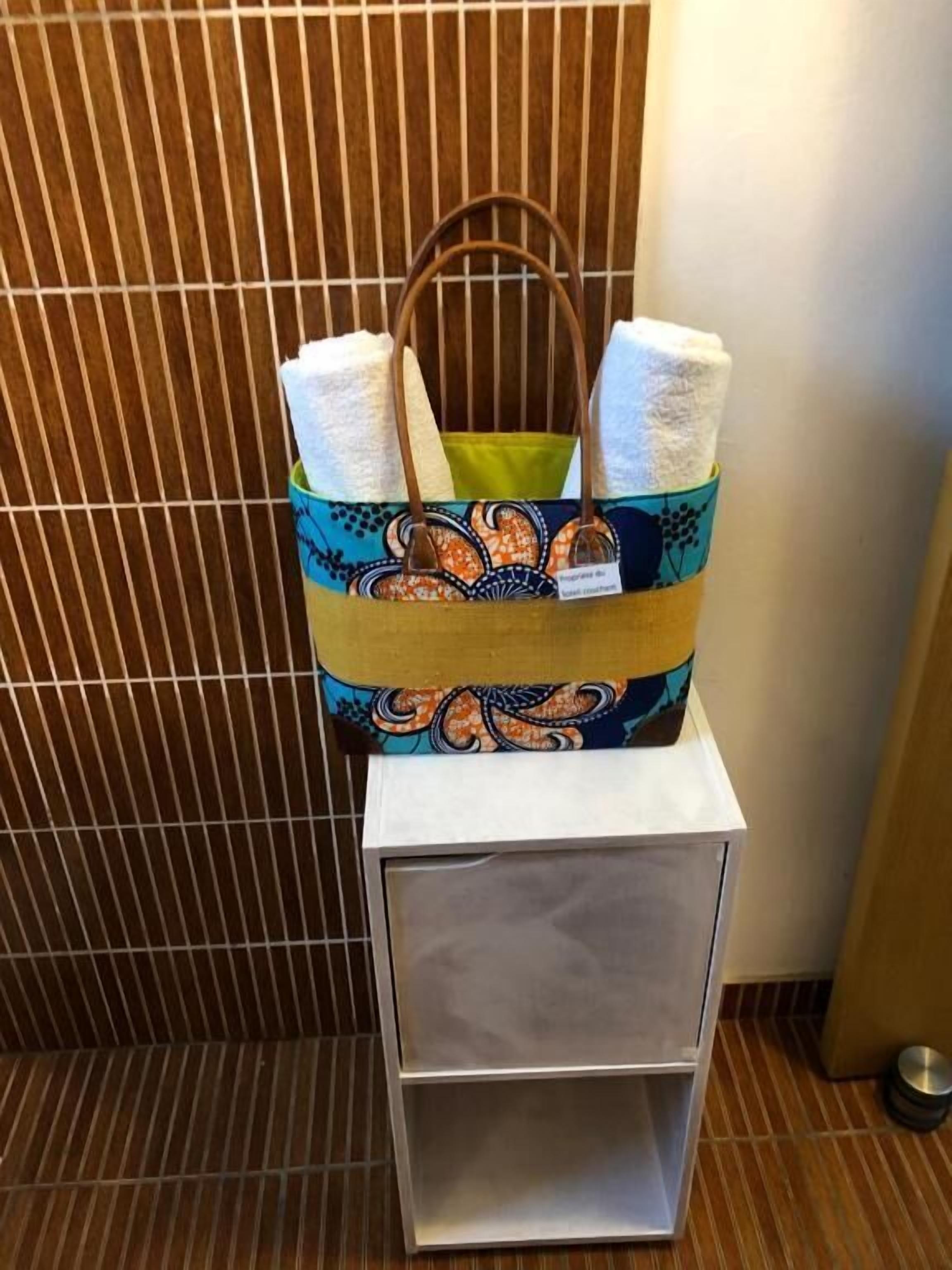 Un bolso de mano estampado con asas, sobre un estante blanco frente a un fondo de madera.