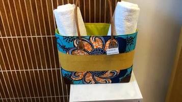 Un bolso de mano estampado con asas, sobre un estante blanco frente a un fondo de madera.