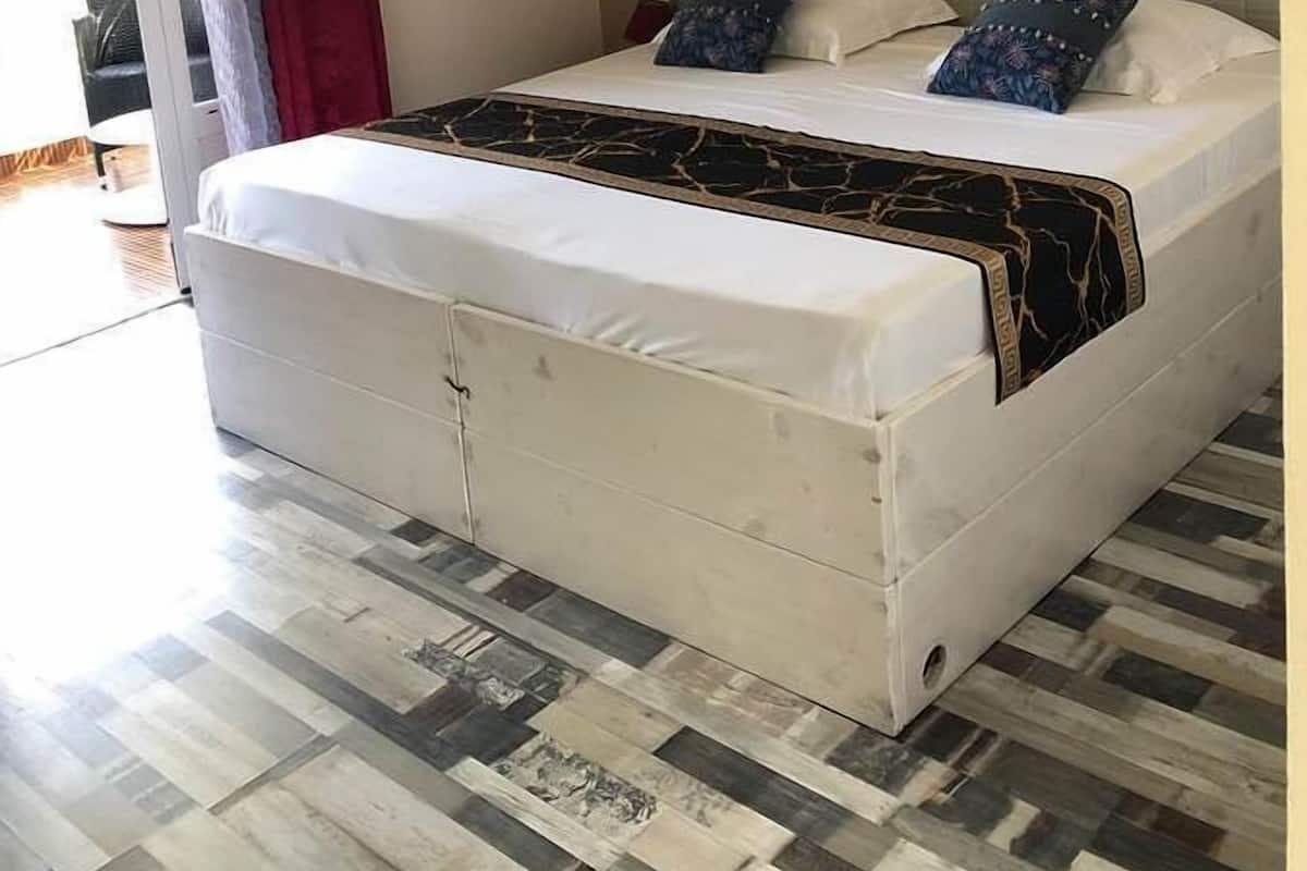 Un dormitorio con cama, una lámpara colgante roja, un equipo de aire acondicionado y vistas al exterior.