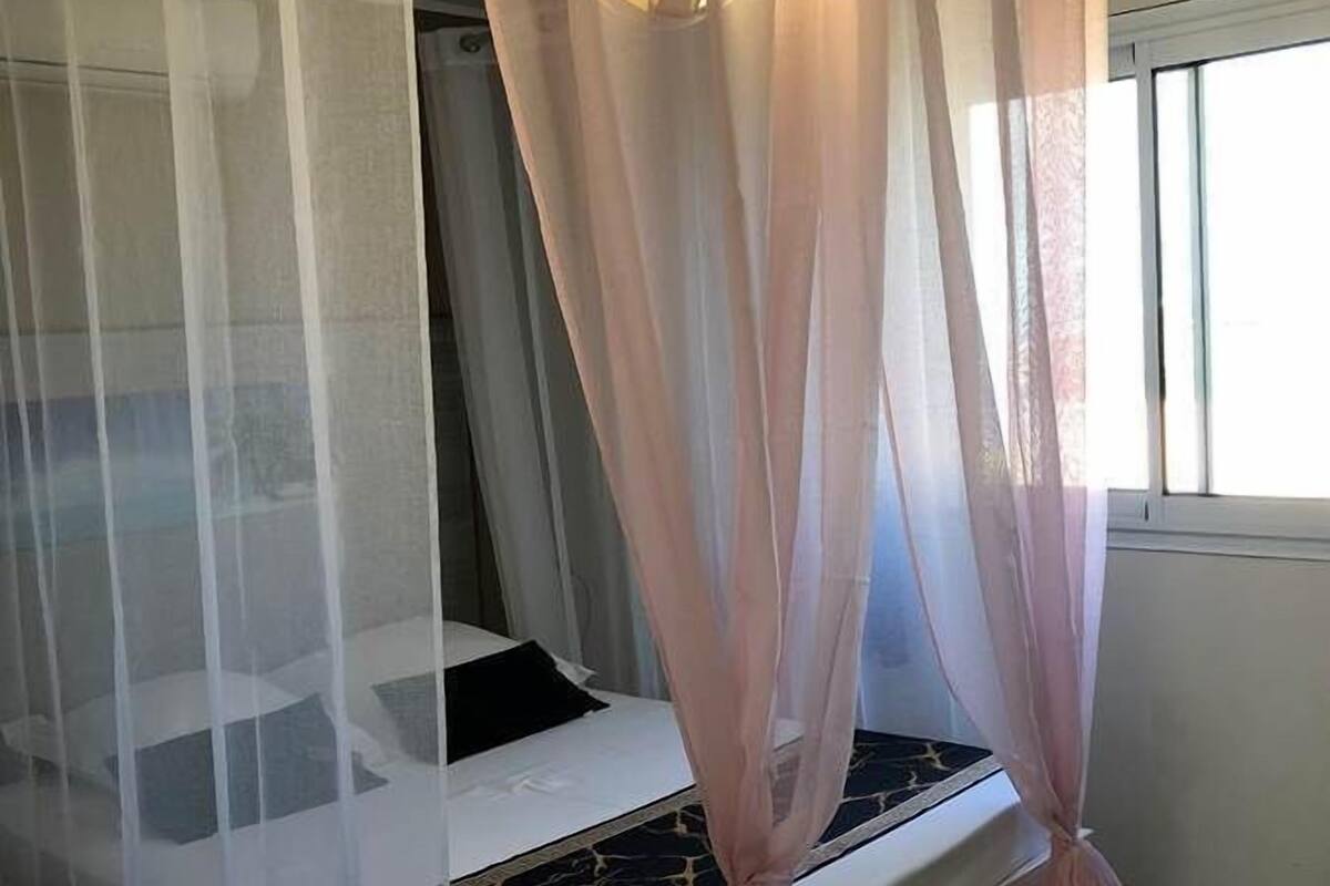 Un dormitorio con cama, ventana y cortina.
