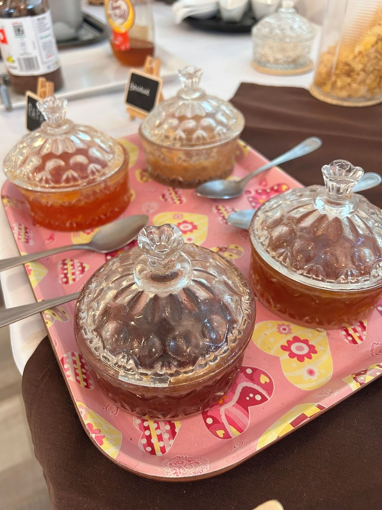 Un plateau avec trois récipients en verre, posé sur une table, et une cuillère dans chacun.