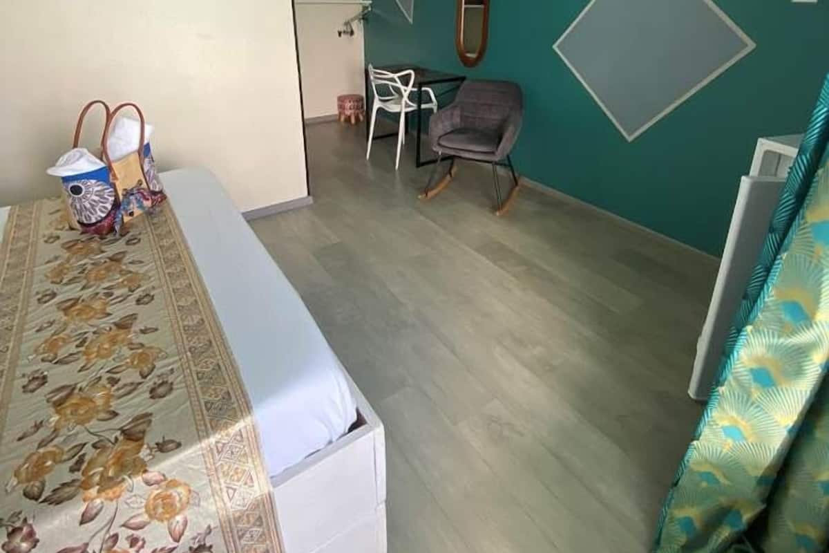Un dormitorio con cama, escritorio, silla y espejo.